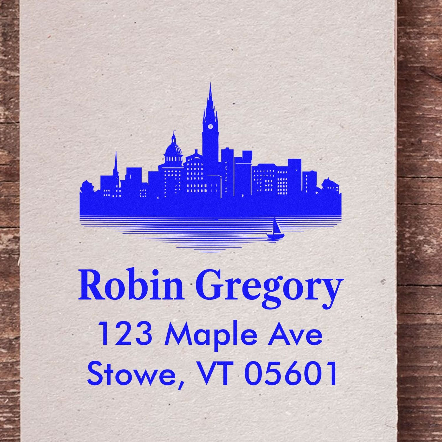 Personalized rubber return address stamp with skyline design for Robin Gregory, 123 Maple Ave, Stowe, VT 05601.
