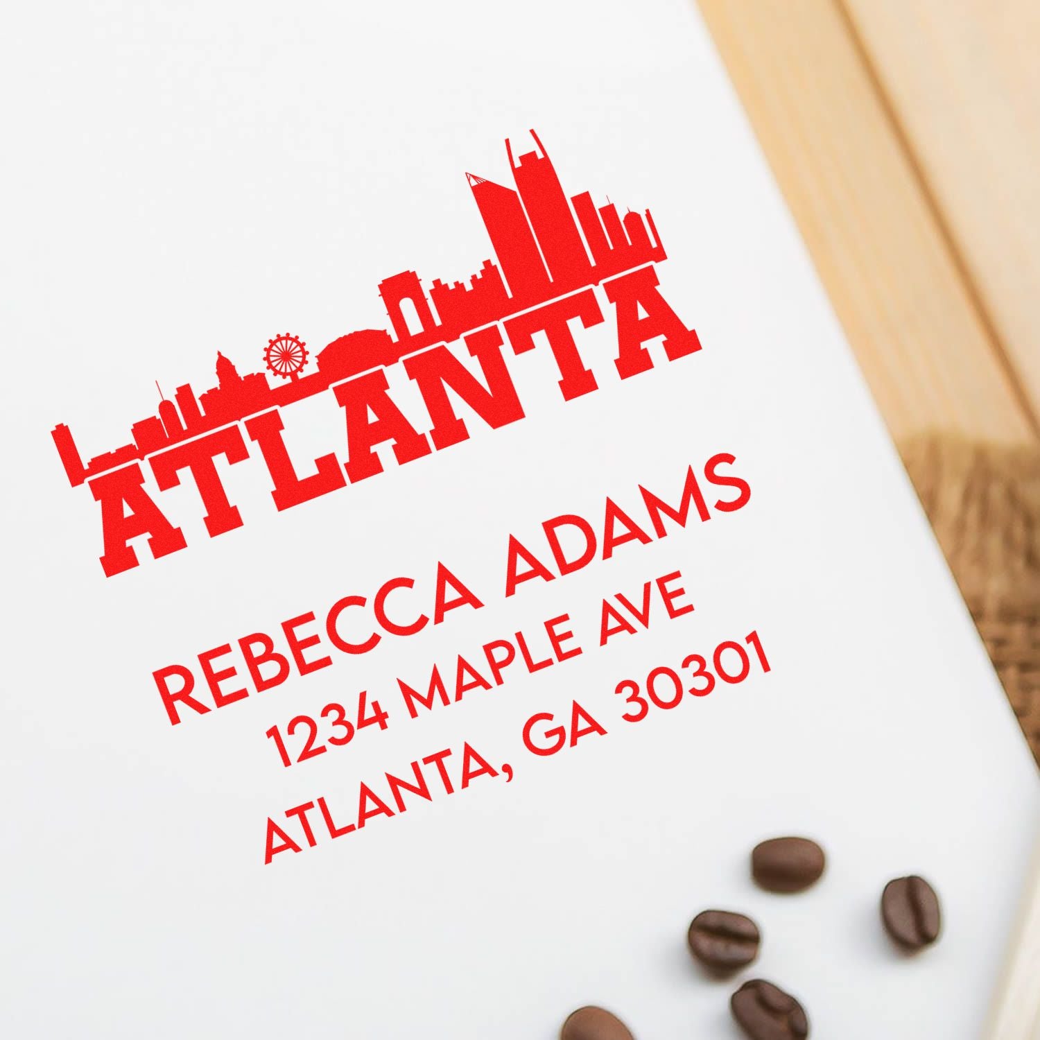 Custom Atlanta address rubber stamp with skyline design and Rebecca Adams mailing address on white paper.