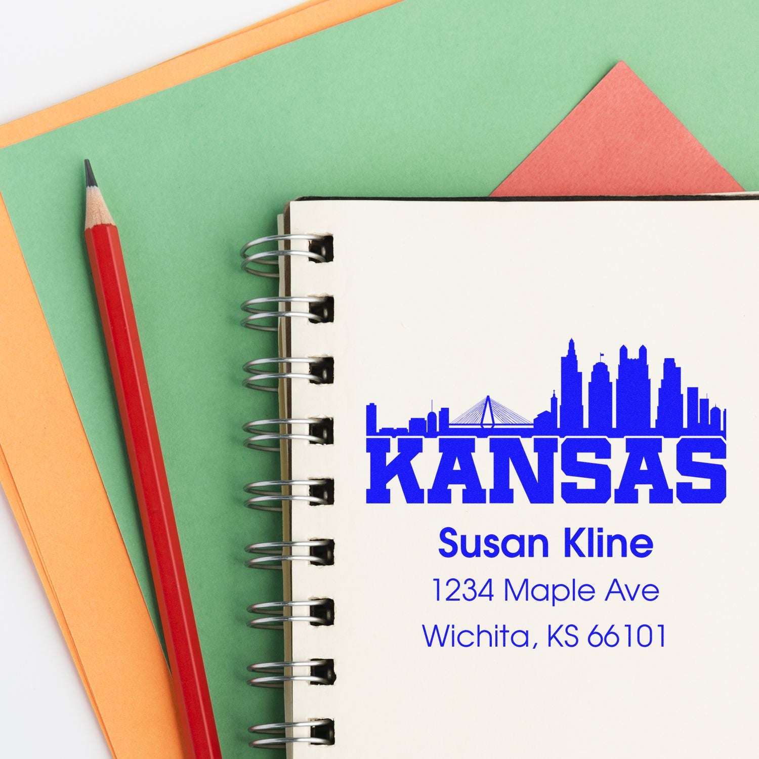 Custom Kansas skyline address rubber stamp sample with name and Wichita, KS address on a notebook.