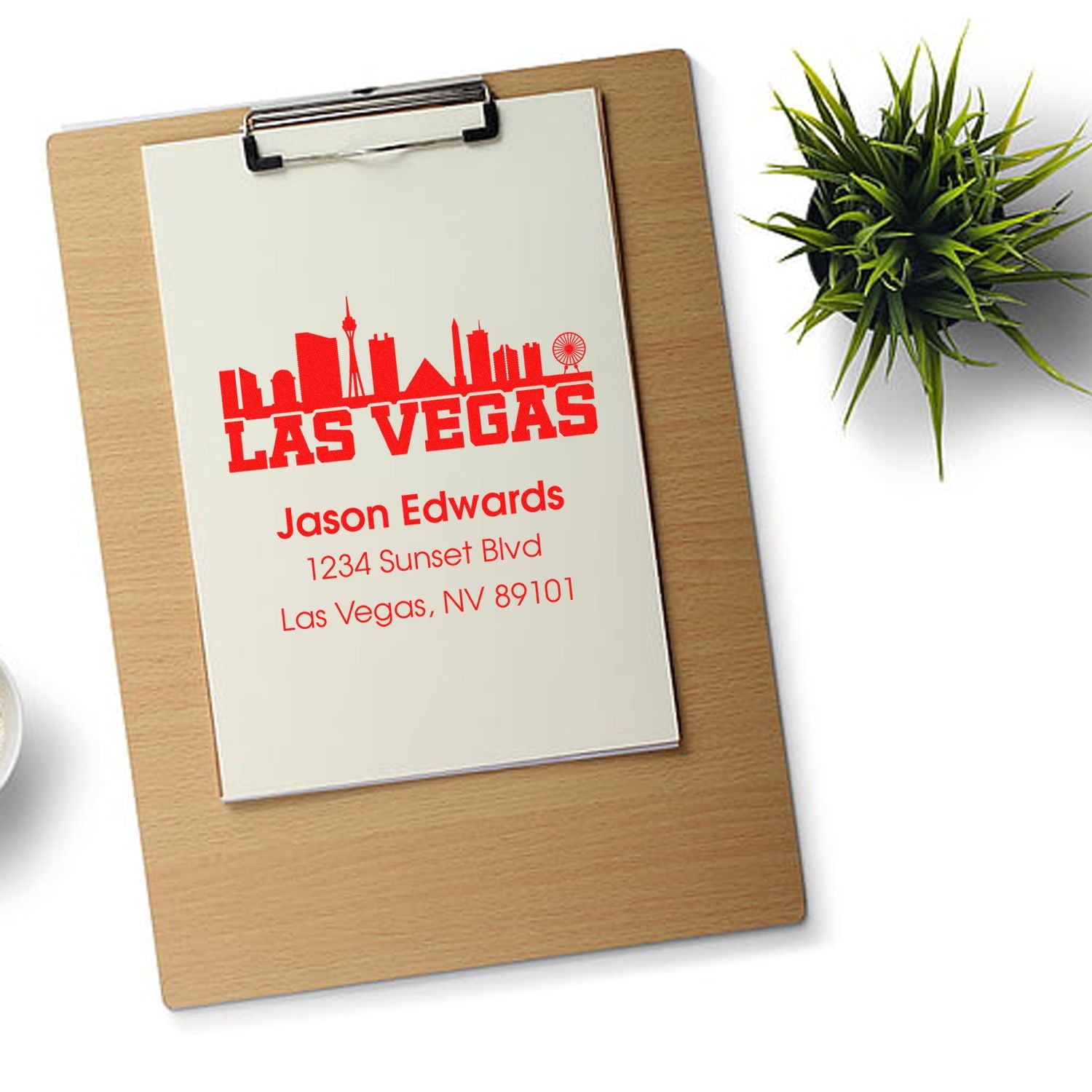 Custom Las Vegas address rubber stamp design with skyline logo, business name, and mailing address on a clipboard.