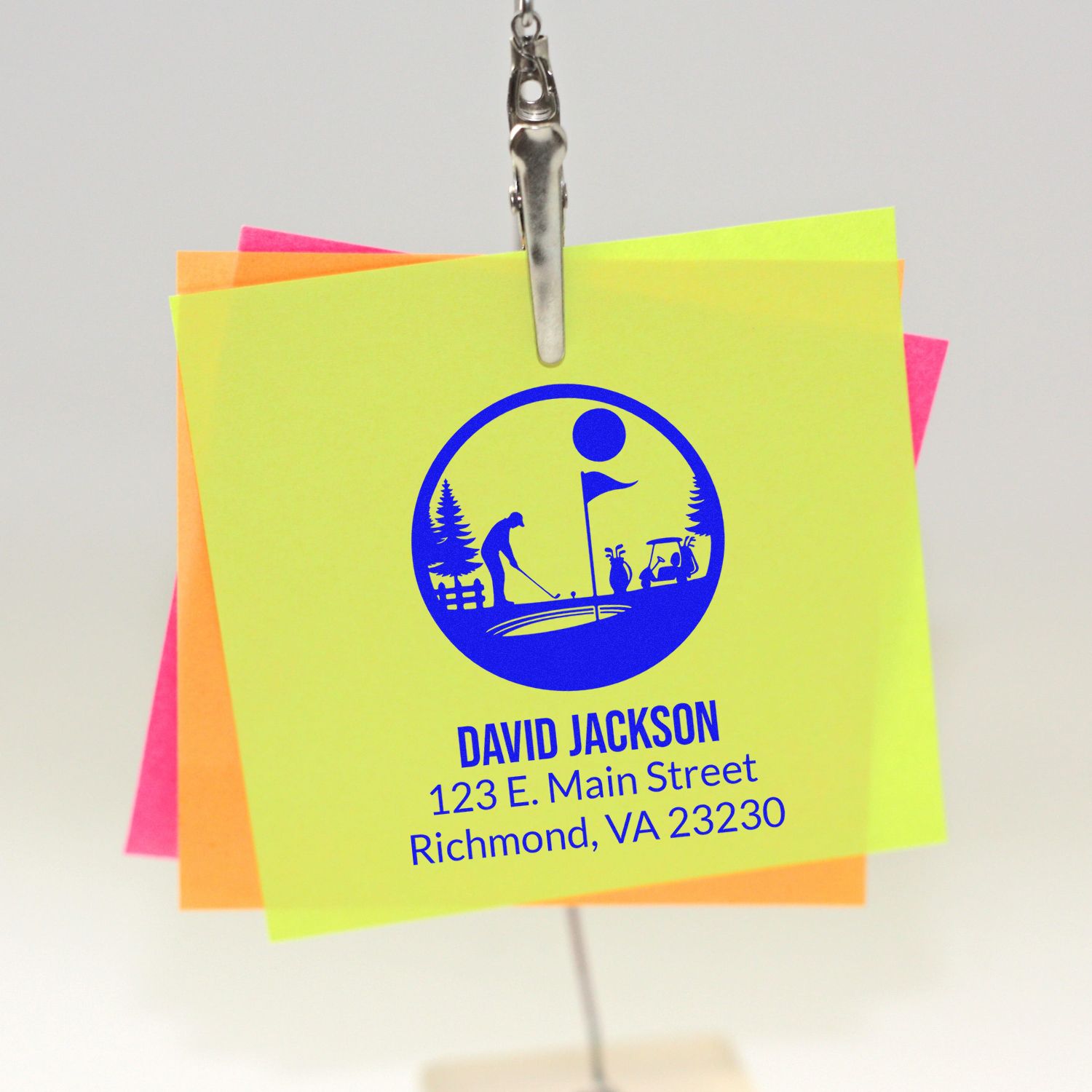Custom rubber stamp with golf logo and return address on neon sticky notes, showing personalized business branding.