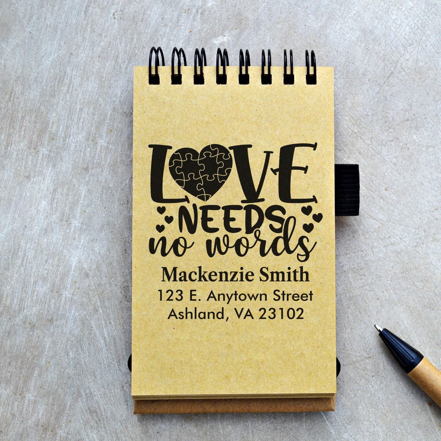 Personalized rubber stamp design on notebook cover reading Love Needs No Words with name and address.