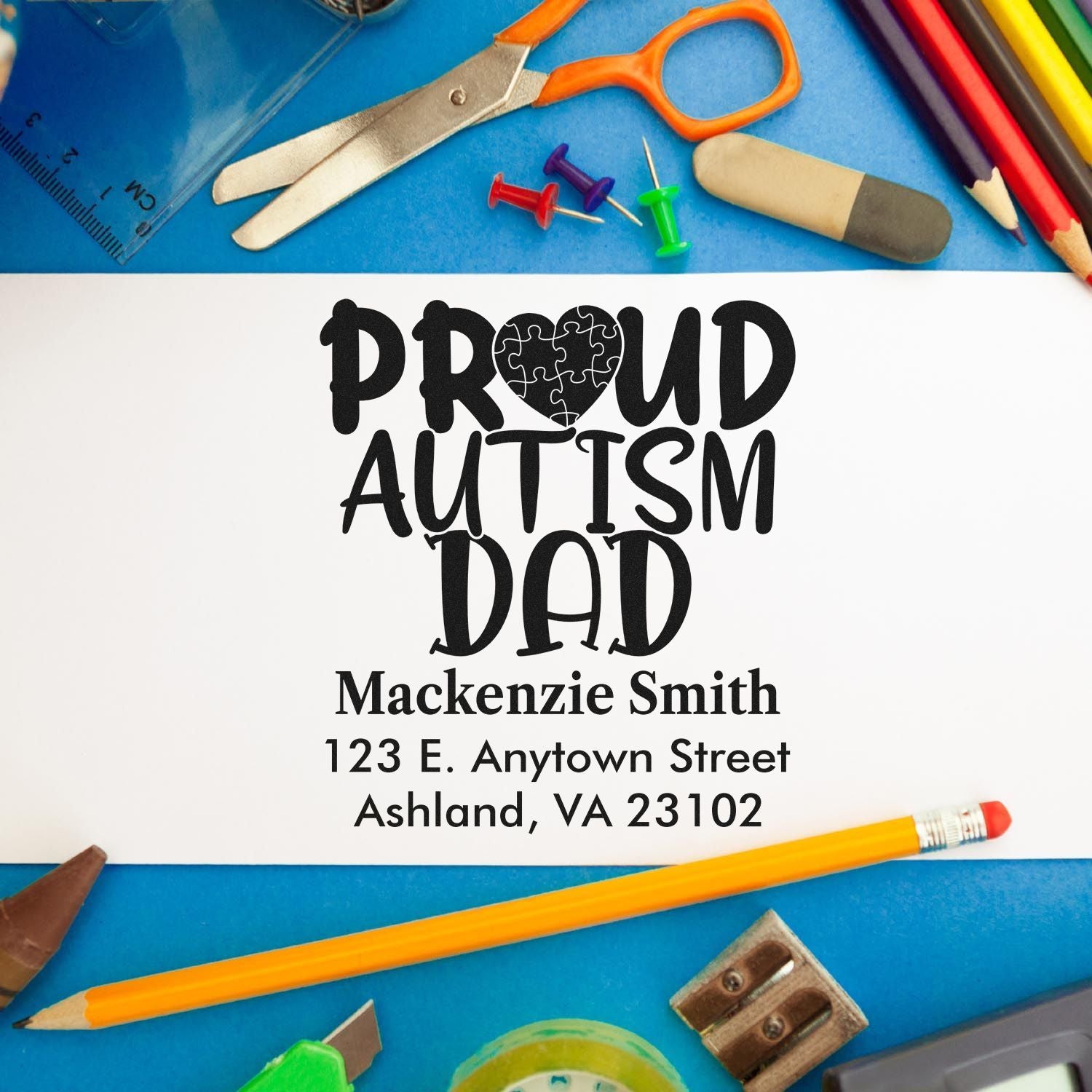 Personalized Proud Autism Dad custom rubber stamp with name and address, surrounded by school supplies for autism awareness.