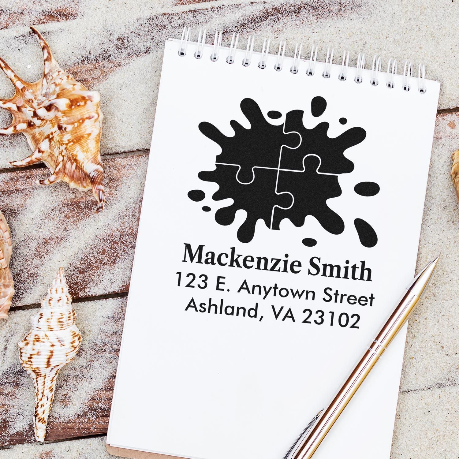 Custom rubber address stamp with logo, name, and mailing address on a notebook for business branding.