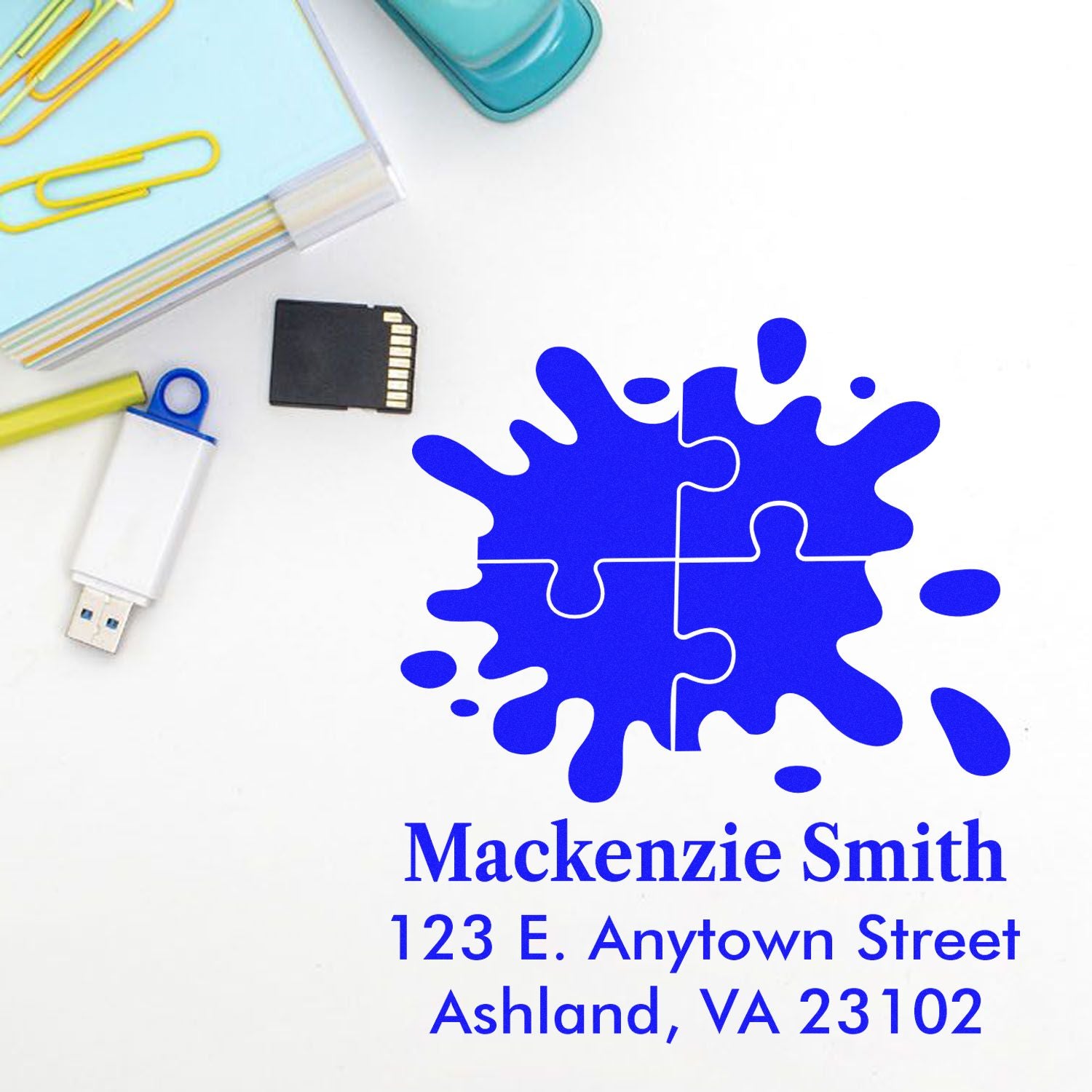 Custom rubber address stamp with blue puzzle splash design, personalized for Mackenzie Smith, Ashland, VA 23102.