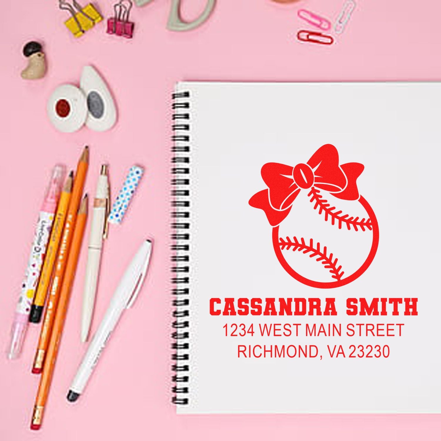 Custom personalized address rubber stamp with baseball bow design for Cassandra Smith, Richmond VA, shown on notebook.