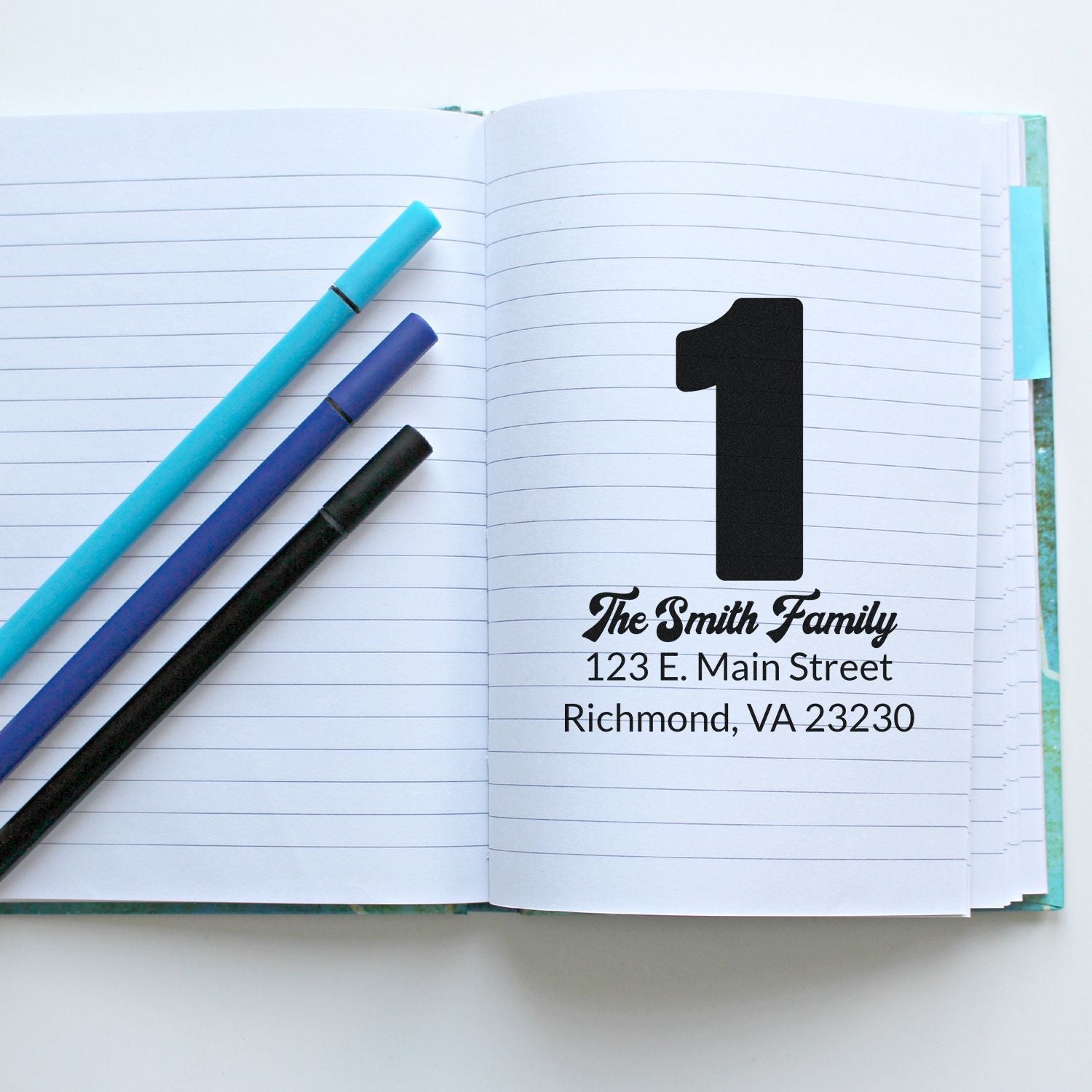Personalized return address rubber stamp for The Smith Family, shown in a notebook with pens for stationery and mailing use.