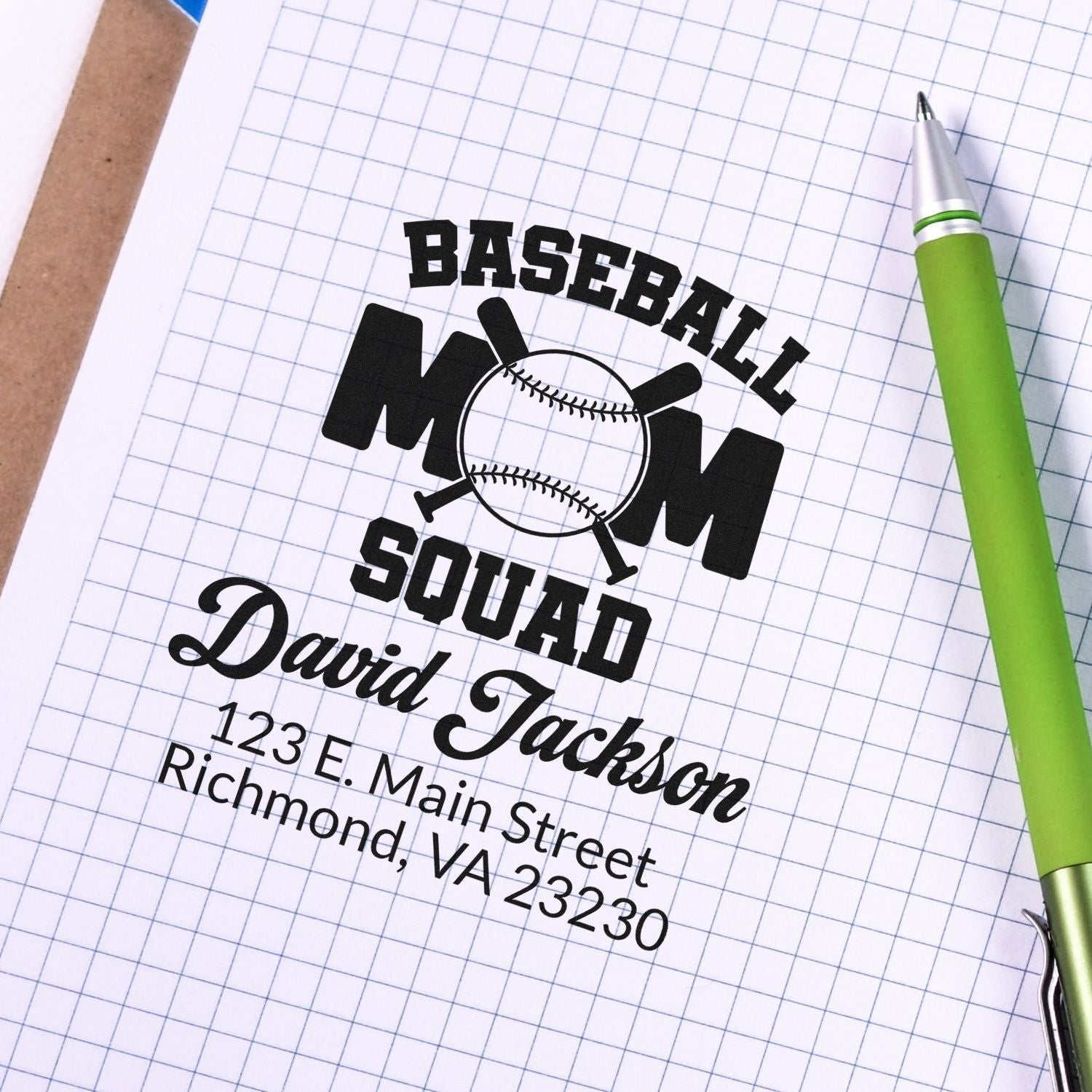 Custom baseball mom squad rubber stamp with personalized name and address on graph paper beside a pen