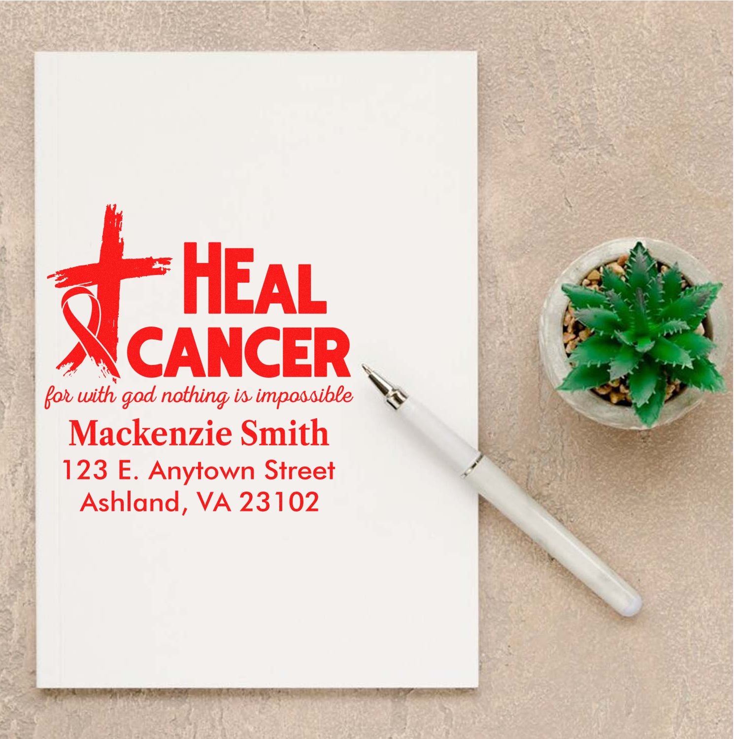 Personalized Heal Cancer rubber stamp with faith ribbon, name and address, shown on a note card with pen and succulent.