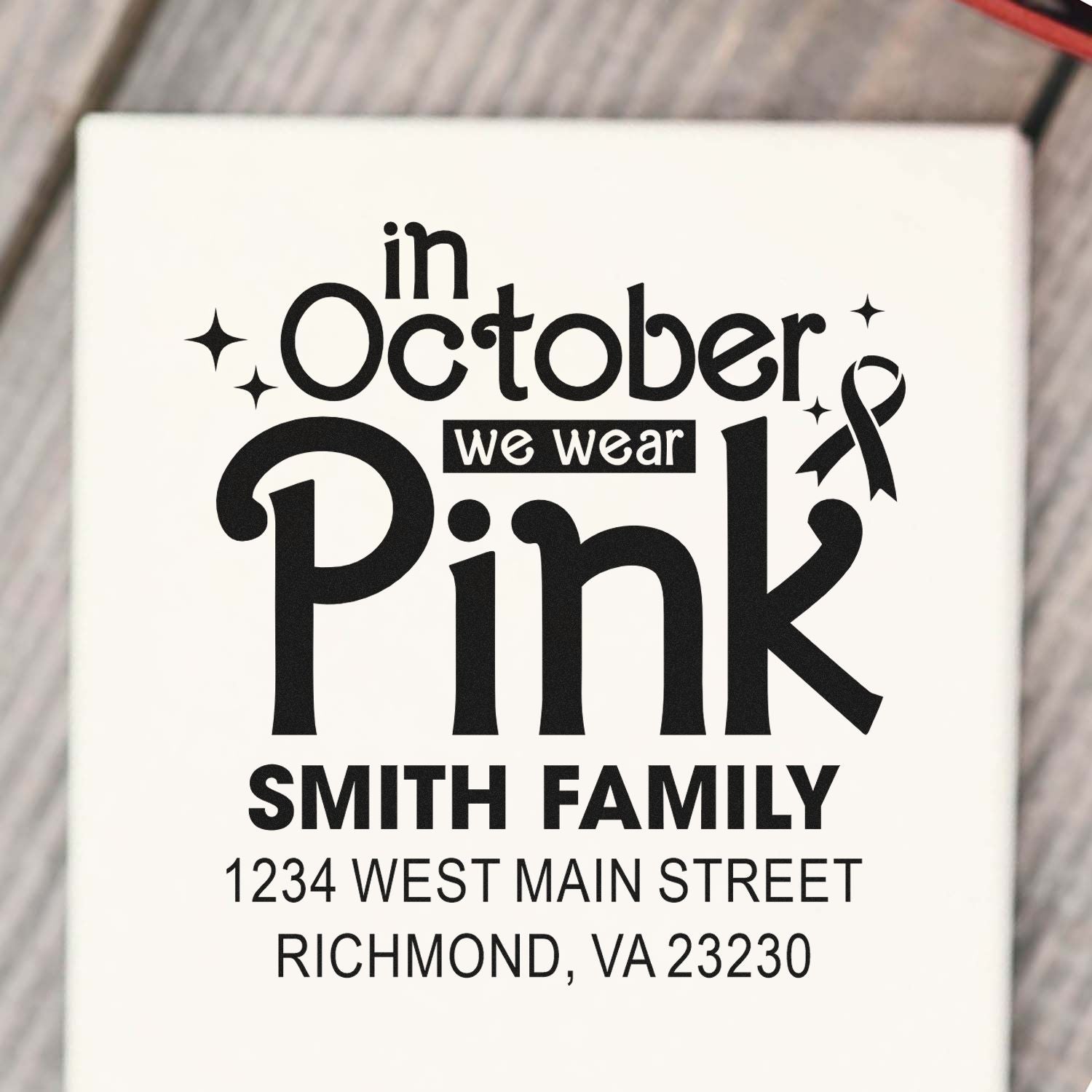 Custom rubber stamp design reading In October We Wear Pink with ribbon, Smith Family name, and return address.