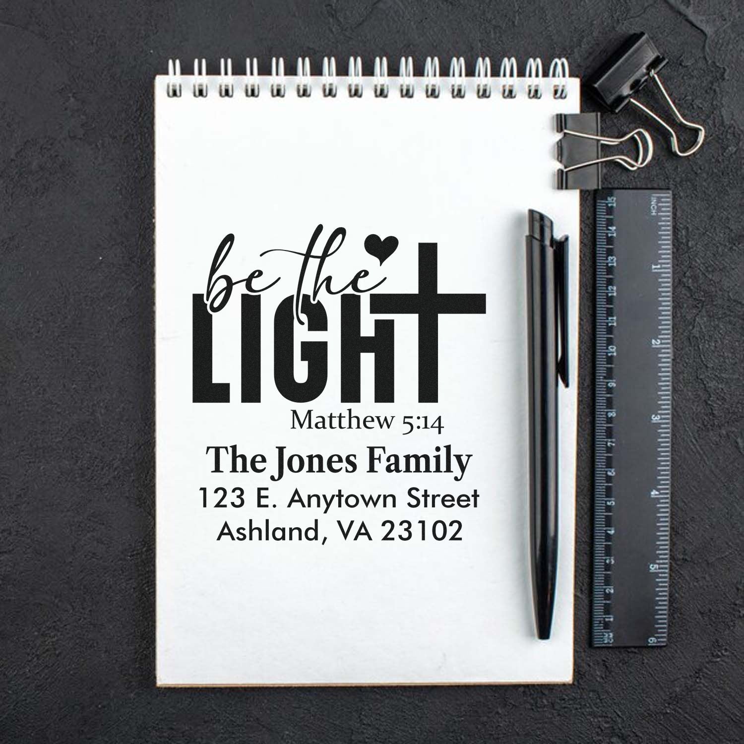 Custom rubber stamp design with Christian Be the Light Matthew 5:14 family return address on notepad mockup.