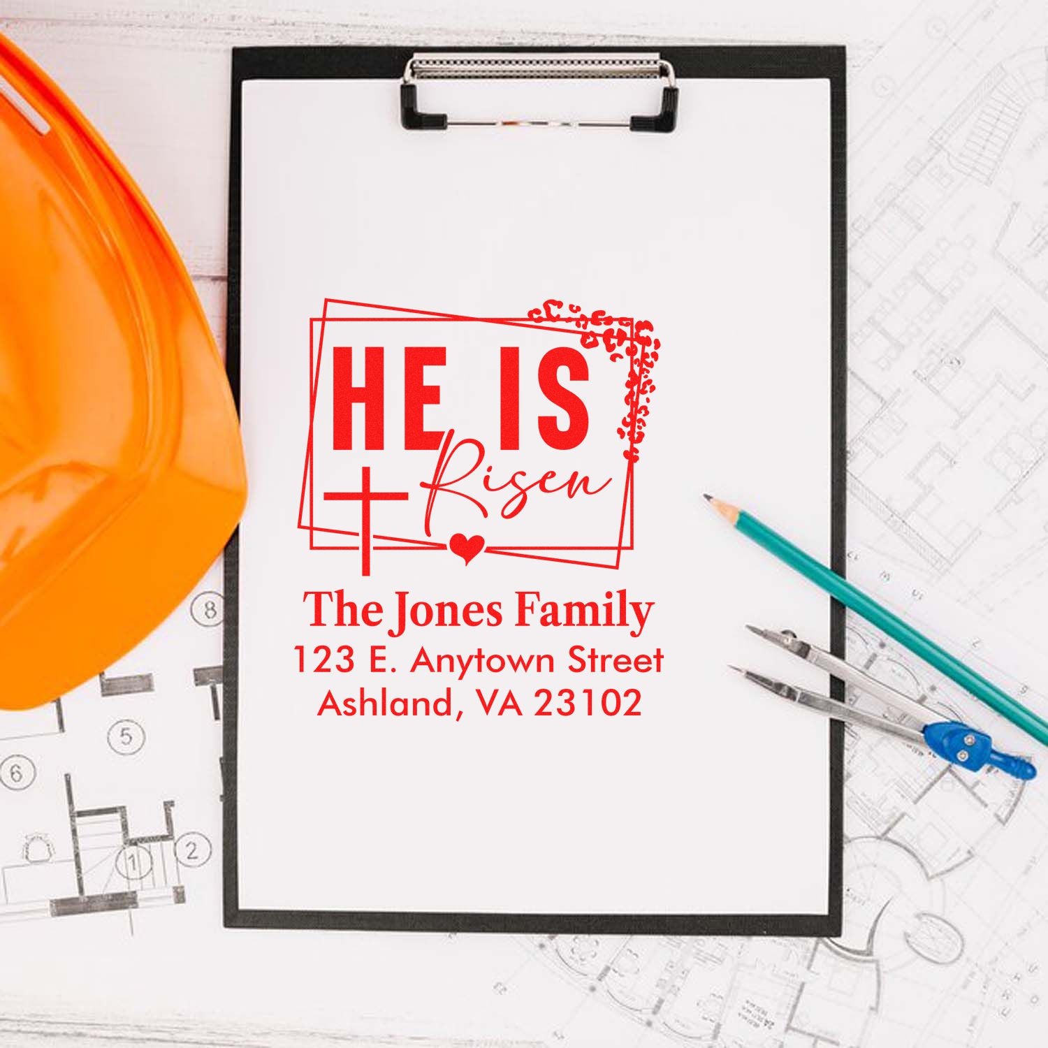 Personalized Christian rubber stamp design, He Is Risen, with family name and address, displayed on clipboard with hard hat and blueprints.