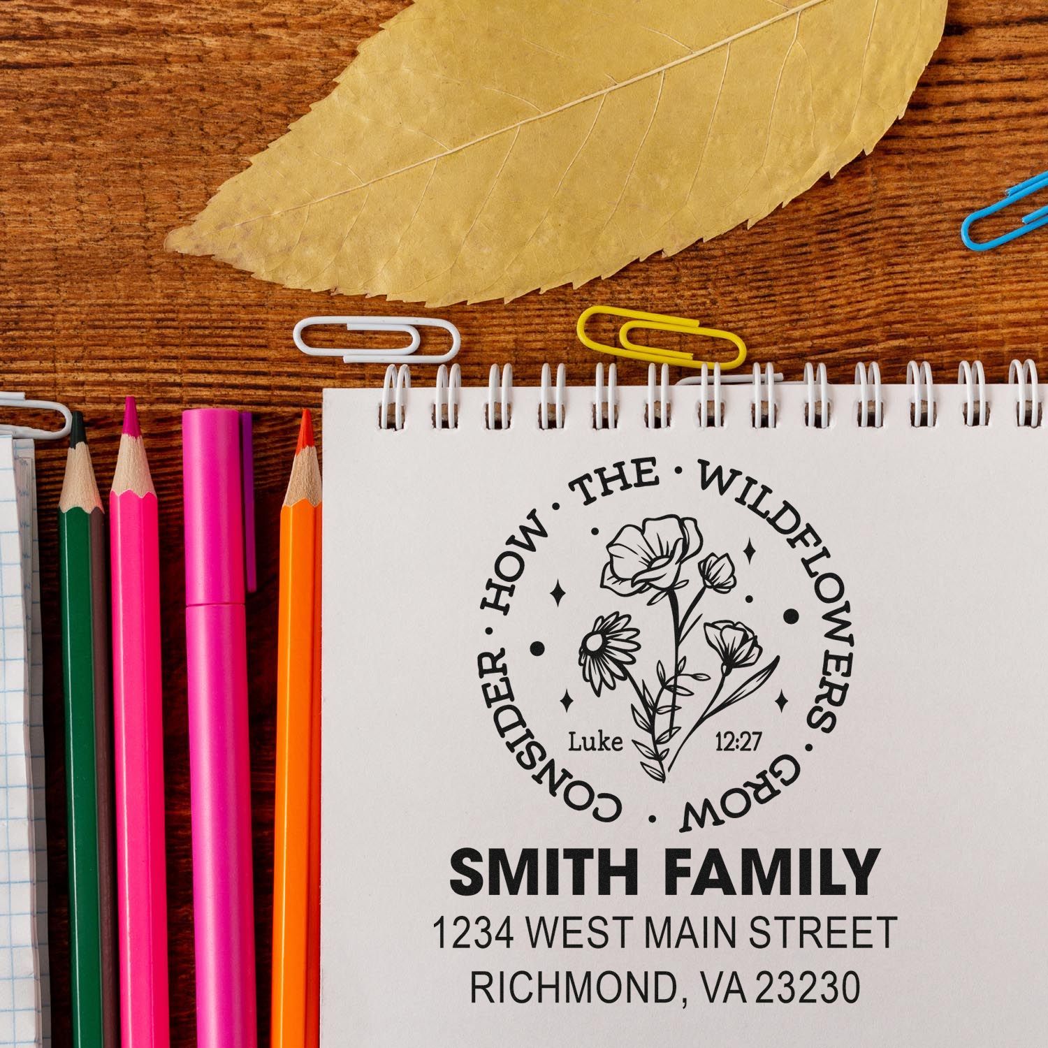 Personalized floral return address rubber stamp for Smith Family, shown on a notebook with stationery and pencils.