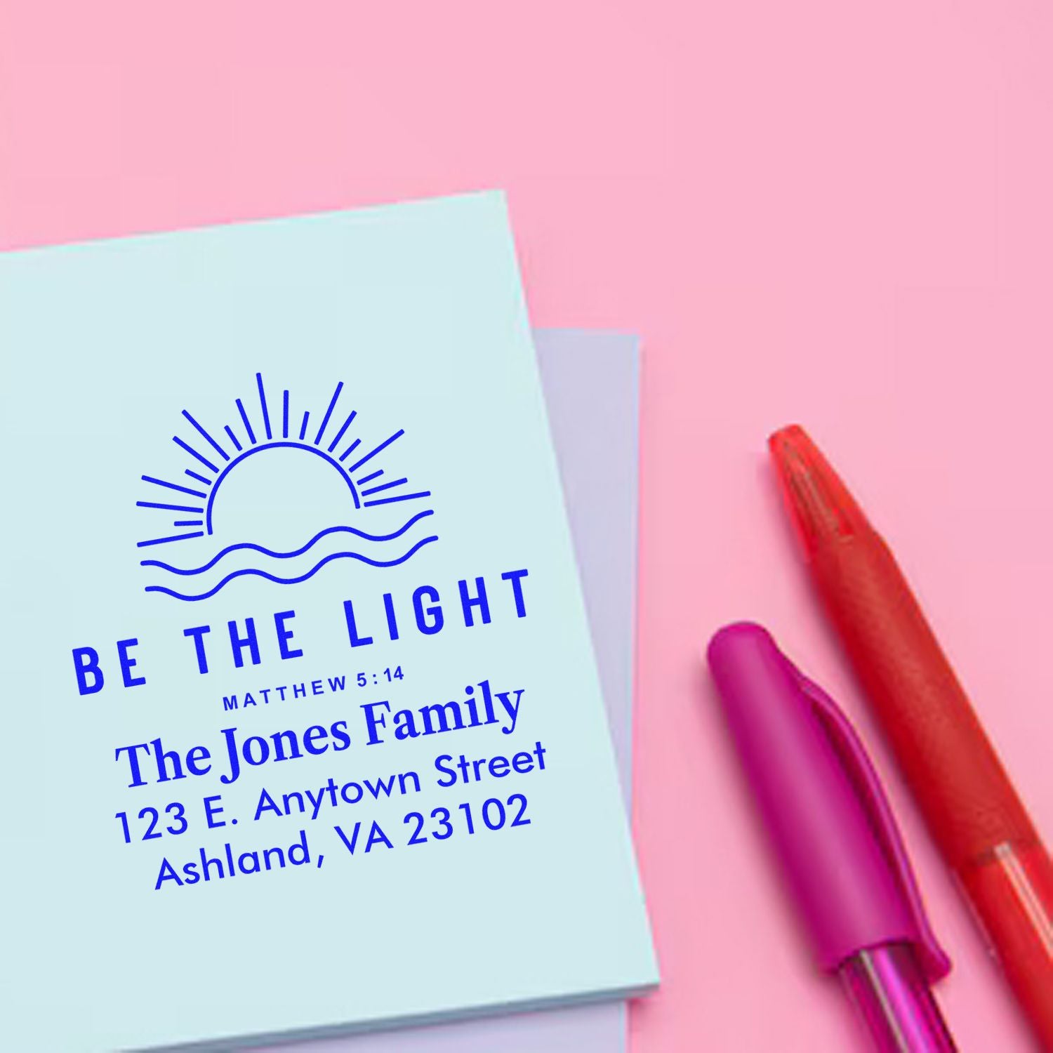 Custom rubber stamp design with Be the Light scripture, family name, and return address on pastel stationery.