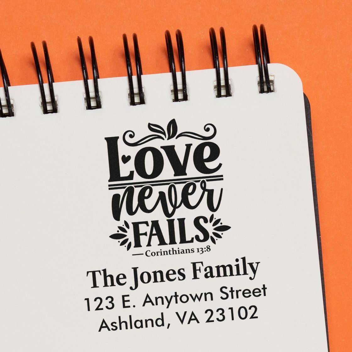 Personalized rubber stamp impression with Love never fails Bible verse and custom family address for wedding or home use.