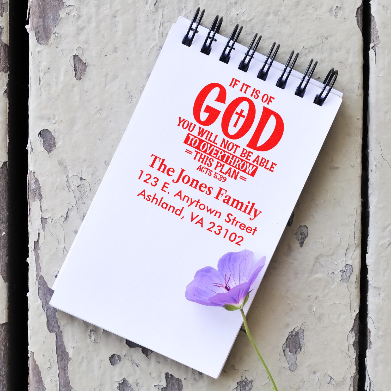 Custom Christian rubber stamp design with Acts 5:39, family name, and address on a notebook.