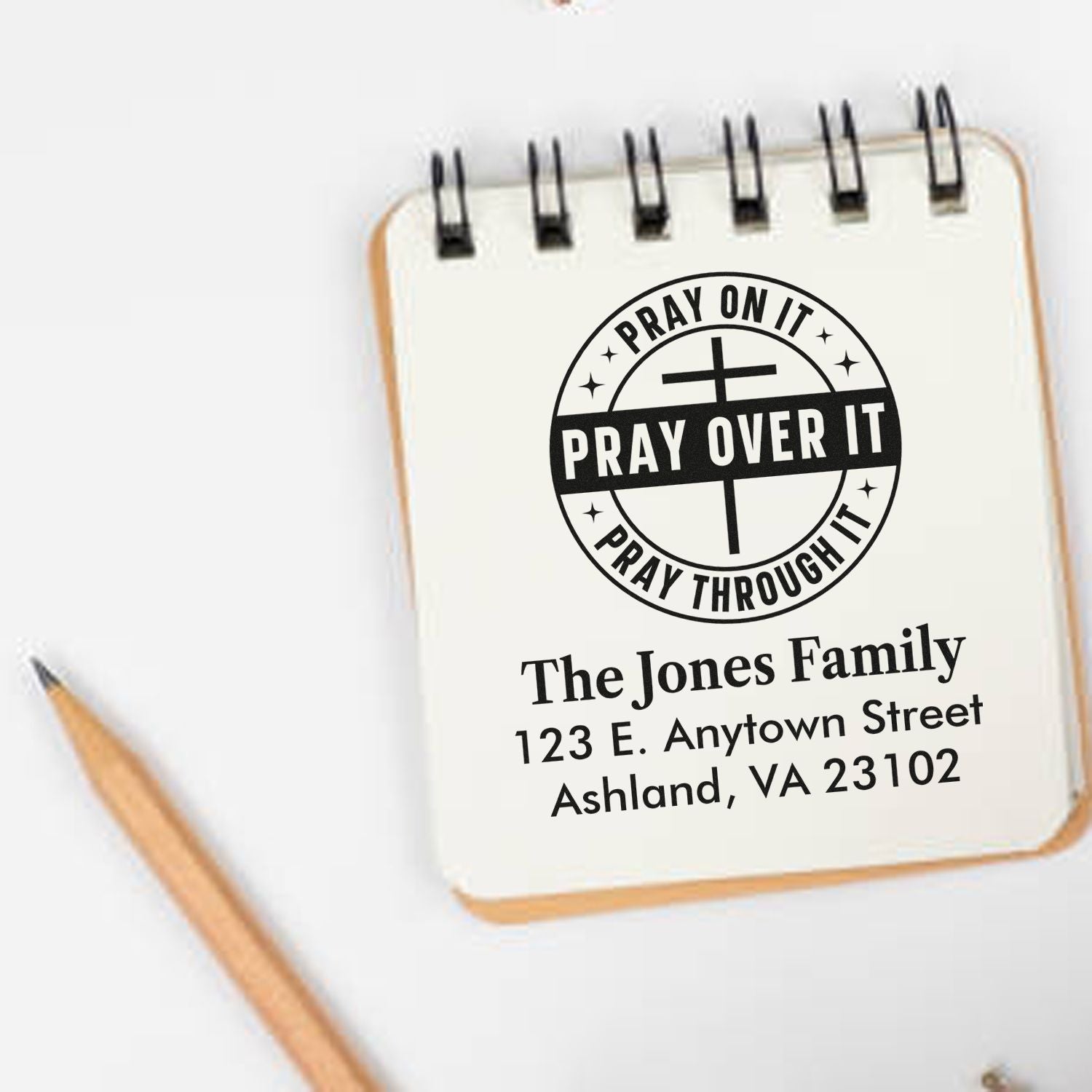 Personalized Christian rubber stamp with Pray Over It design and family address on a notebook.