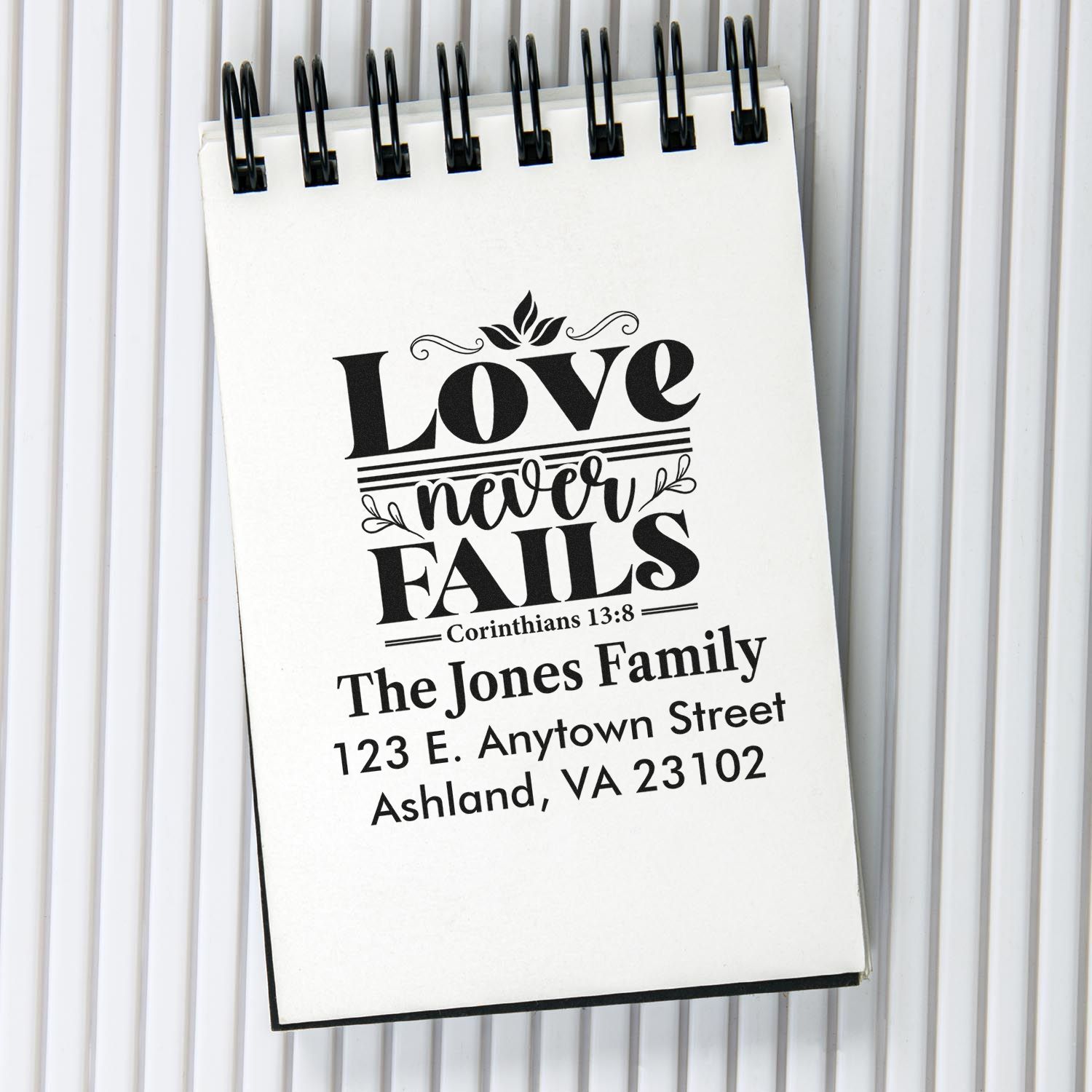 Custom rubber stamp with Bible verse Love never fails and personalized family return address for Christian stationery.