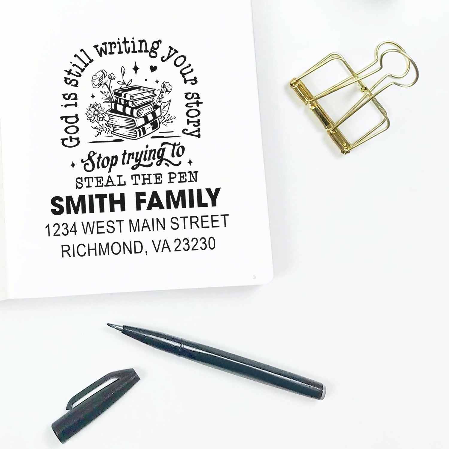 Custom address rubber stamp proof with family name, return address, and floral book design on notebook page
