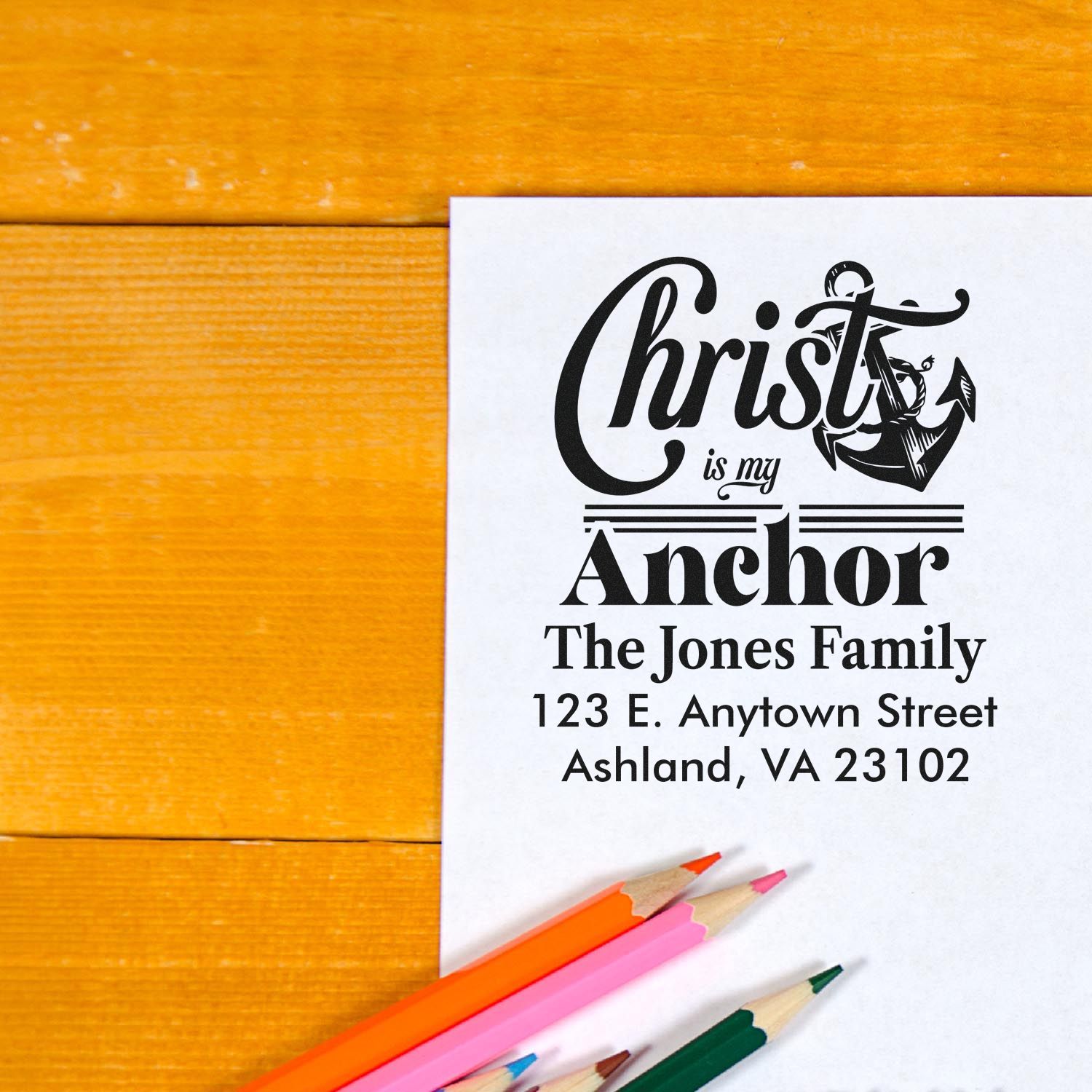 Personalized rubber stamp design reading Christ is my Anchor with The Jones Family address, shown on paper with colored pencils.