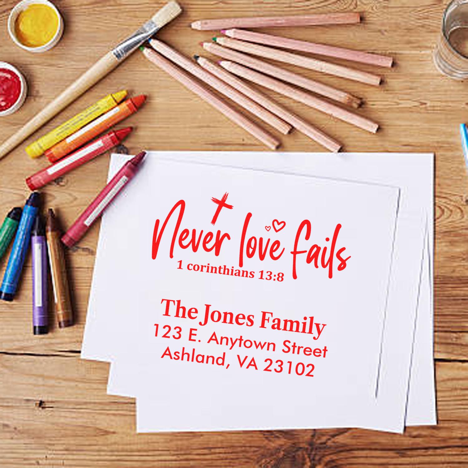 Personalized rubber stamp mockup with scripture quote, Never love fails, and custom return address on stationery.