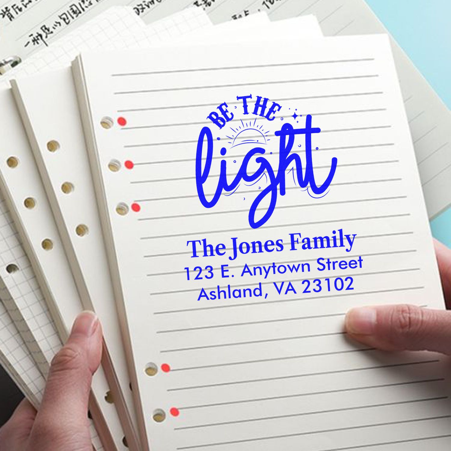 Custom family address rubber stamp with Be the Light design on lined notebook pages.
