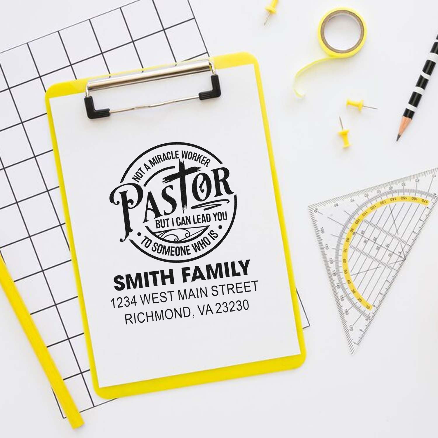 Custom pastor family address rubber stamp design with church quote, name, and return address on clipboard.