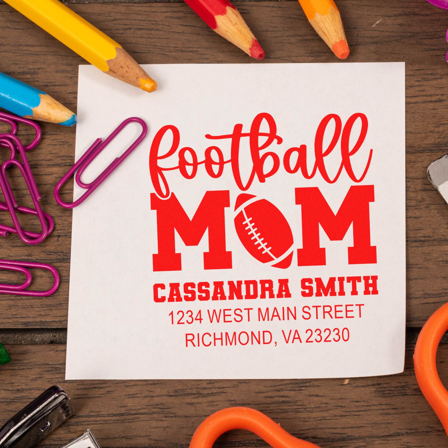 Personalized football mom return address rubber stamp with custom name and address on paper with school supplies.