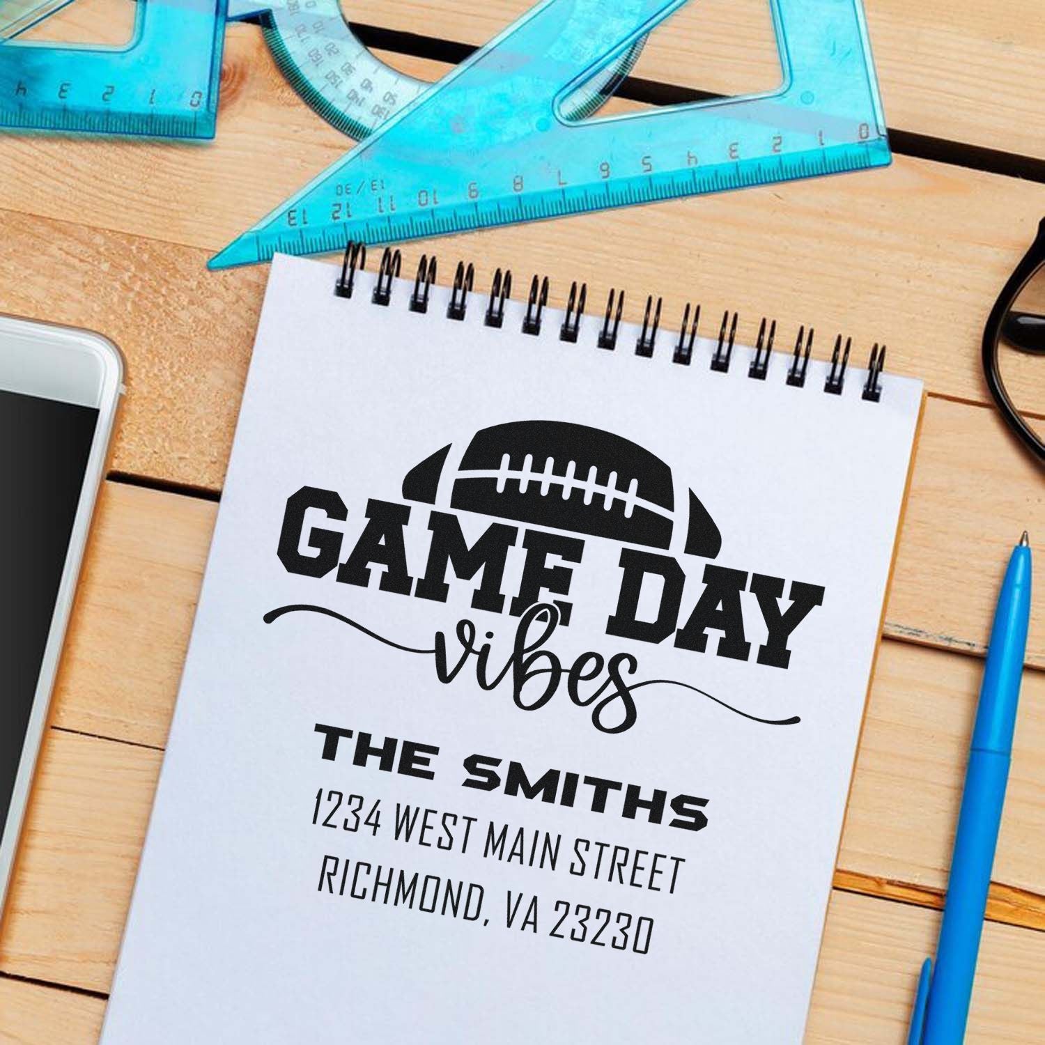 Custom football game day vibes rubber stamp mockup with family name and address on notepad, ideal for personalized sports stationery.