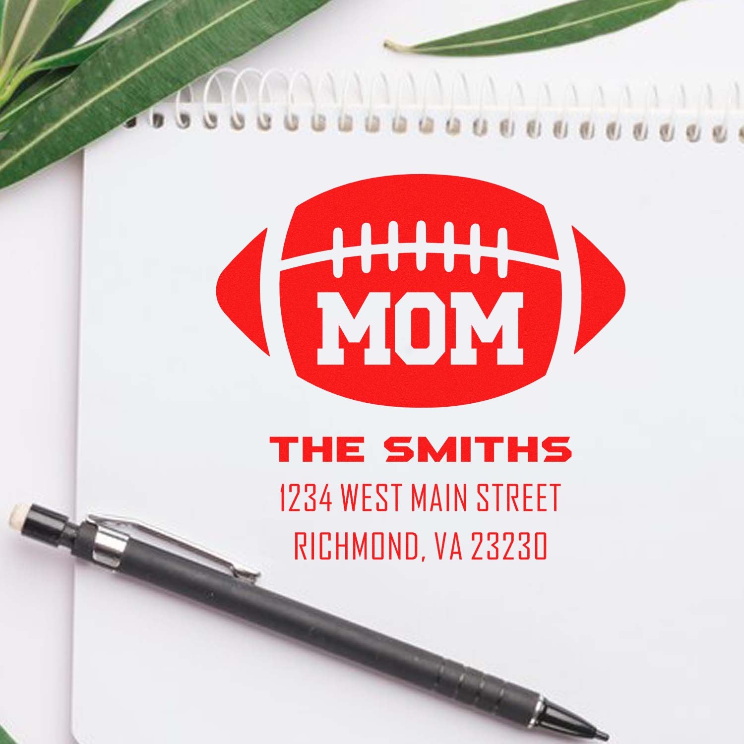 Personalized football mom rubber stamp design with The Smiths name and address in bold red on a notebook.