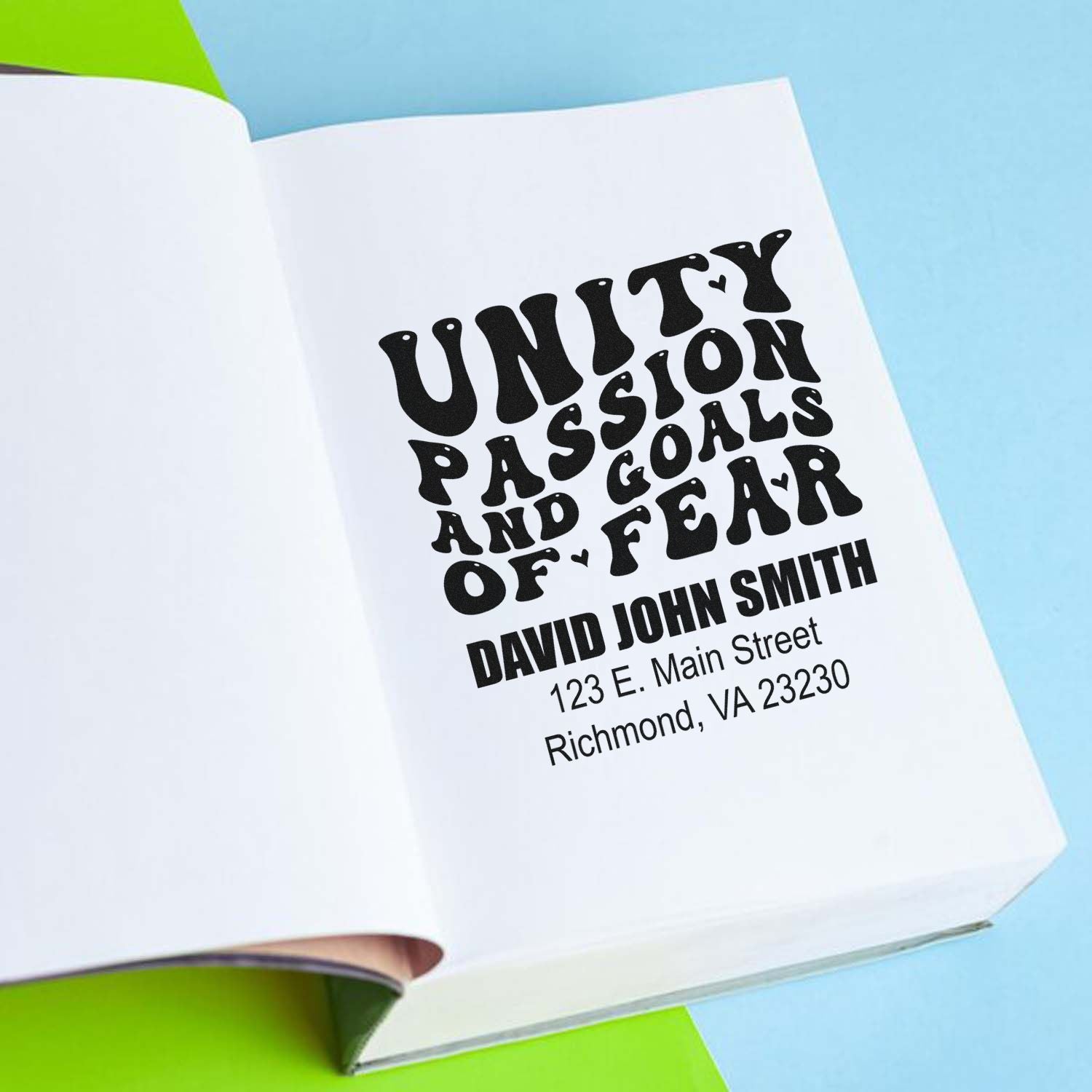 Custom rubber stamp imprint reading Unity, Passion, Goals and Fear with personalized name and address in a notebook.