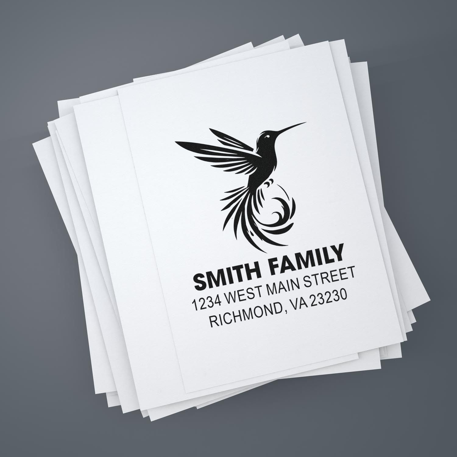 Custom return address rubber stamp with hummingbird logo and Smith Family address on stacked paper cards