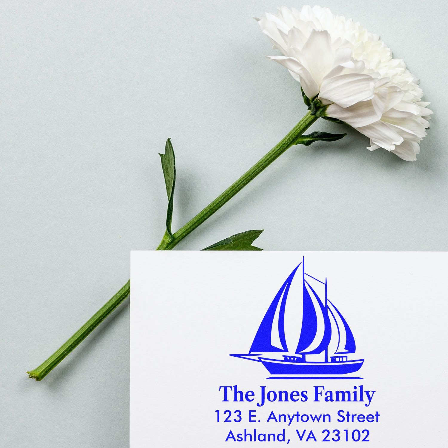 Personalized return address rubber stamp with sailboat logo for The Jones Family, blue ink on card.