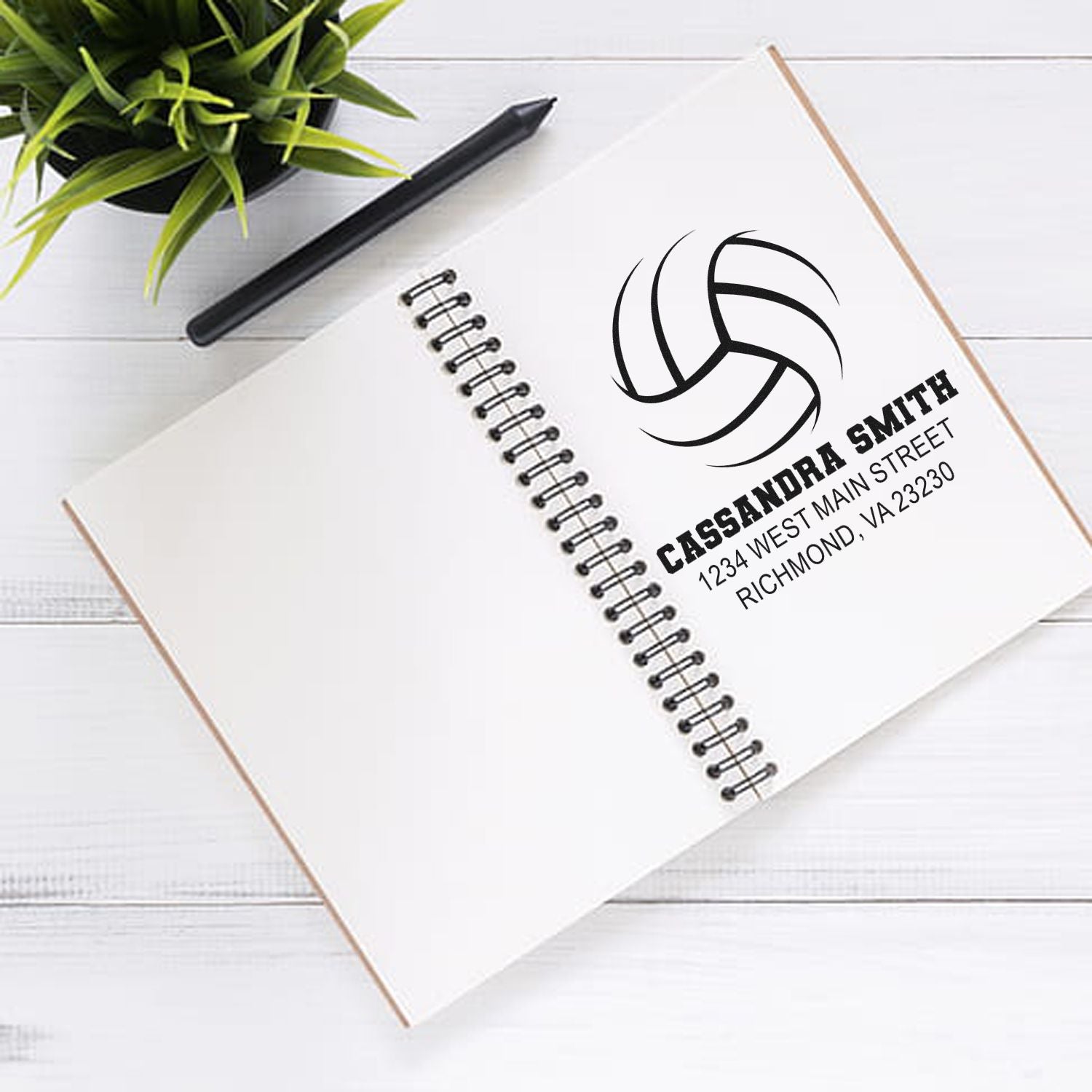 Custom rubber stamp with logo, name, and address on notebook for business branding and personalized stationery.