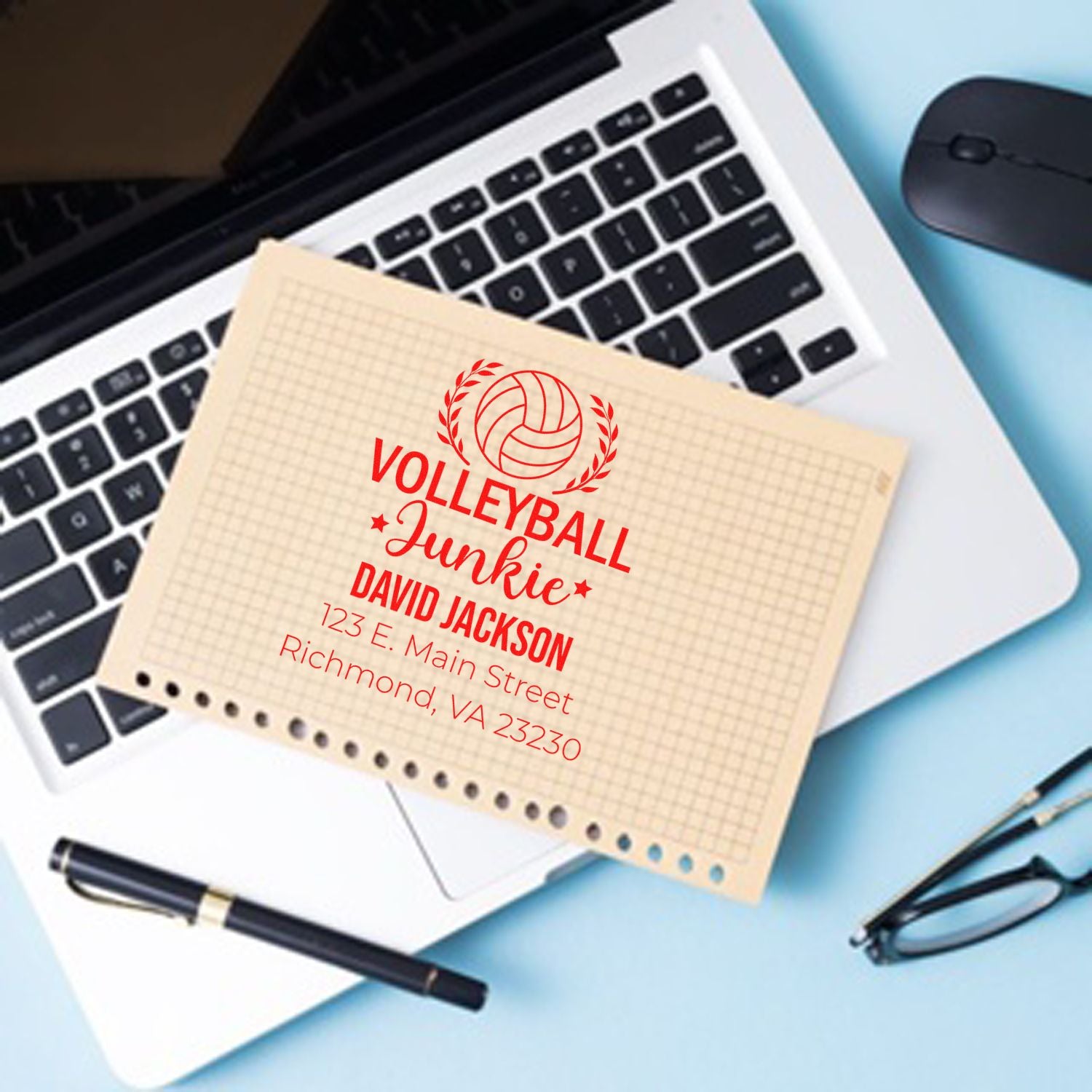 Personalized volleyball return address rubber stamp with name and address, shown on paper over a laptop.