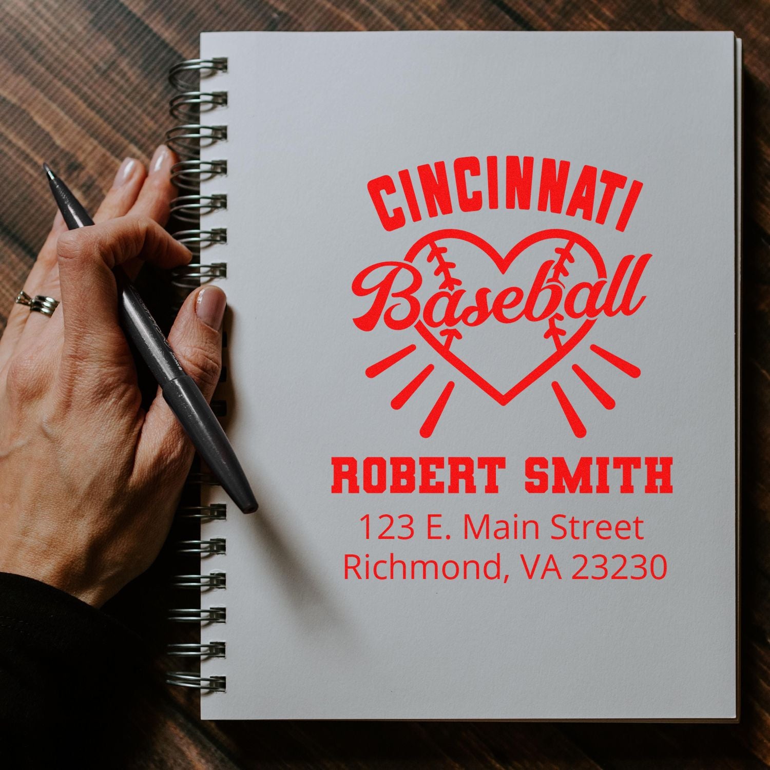 Custom Cincinnati baseball rubber stamp with name and address, shown in red on a notebook for personalized branding.