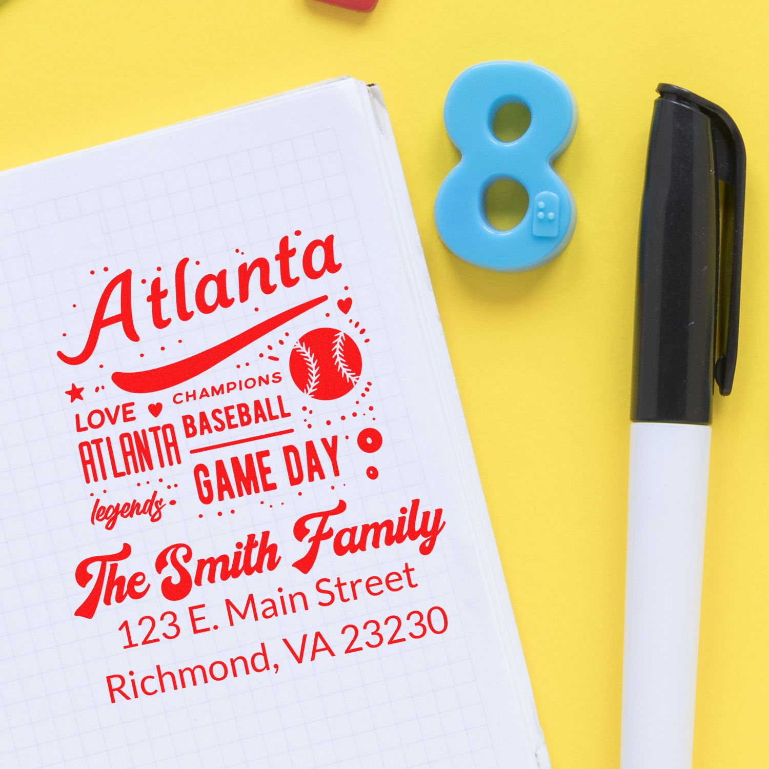 Personalized Atlanta baseball family rubber stamp design with custom address details on notebook beside a marker.
