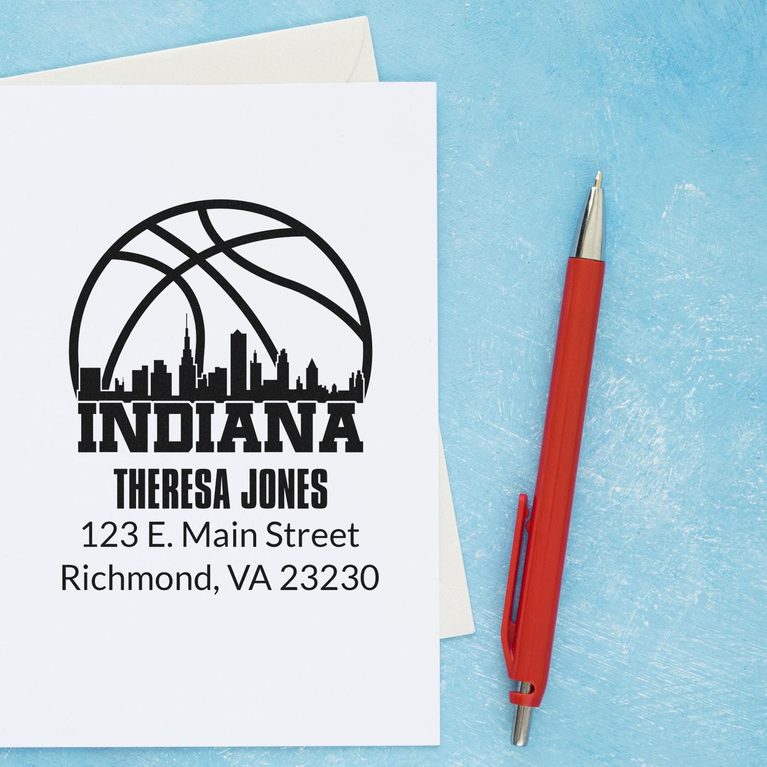Custom Indiana basketball return address rubber stamp with name and street address on stationery, shown beside a red pen.