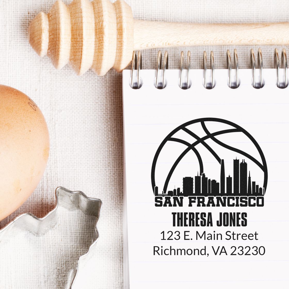 Custom return address rubber stamp with San Francisco skyline, name, and mailing address on a notebook.