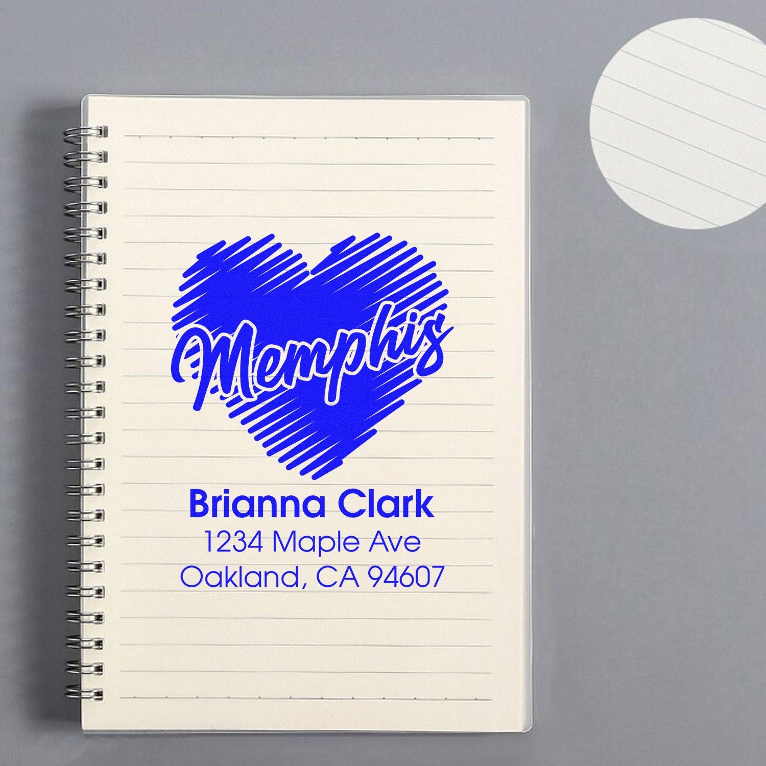 Personalized Memphis return address rubber stamp with heart logo, shown on a notebook for custom stationery branding.