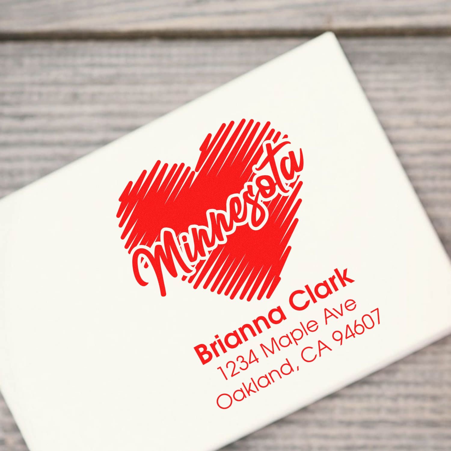 Custom rubber address stamp with red heart design and Brianna Clark mailing address on white envelope.