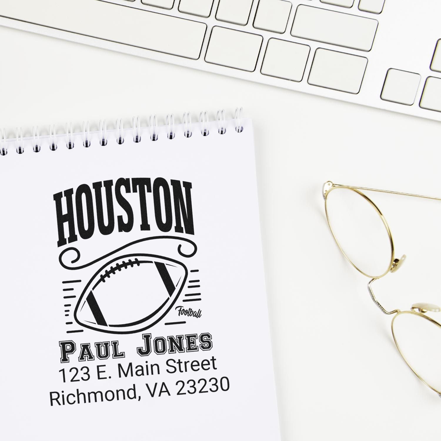 Custom Houston football rubber stamp design with name and address, shown in a notebook on a clean workspace.