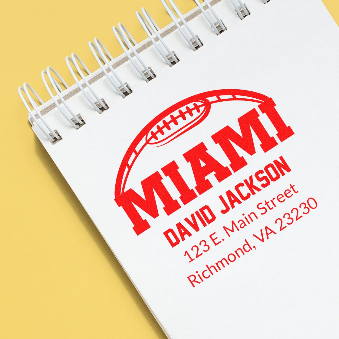 Personalized Miami rubber stamp for David Jackson with football logo, name, and address on a notebook page.
