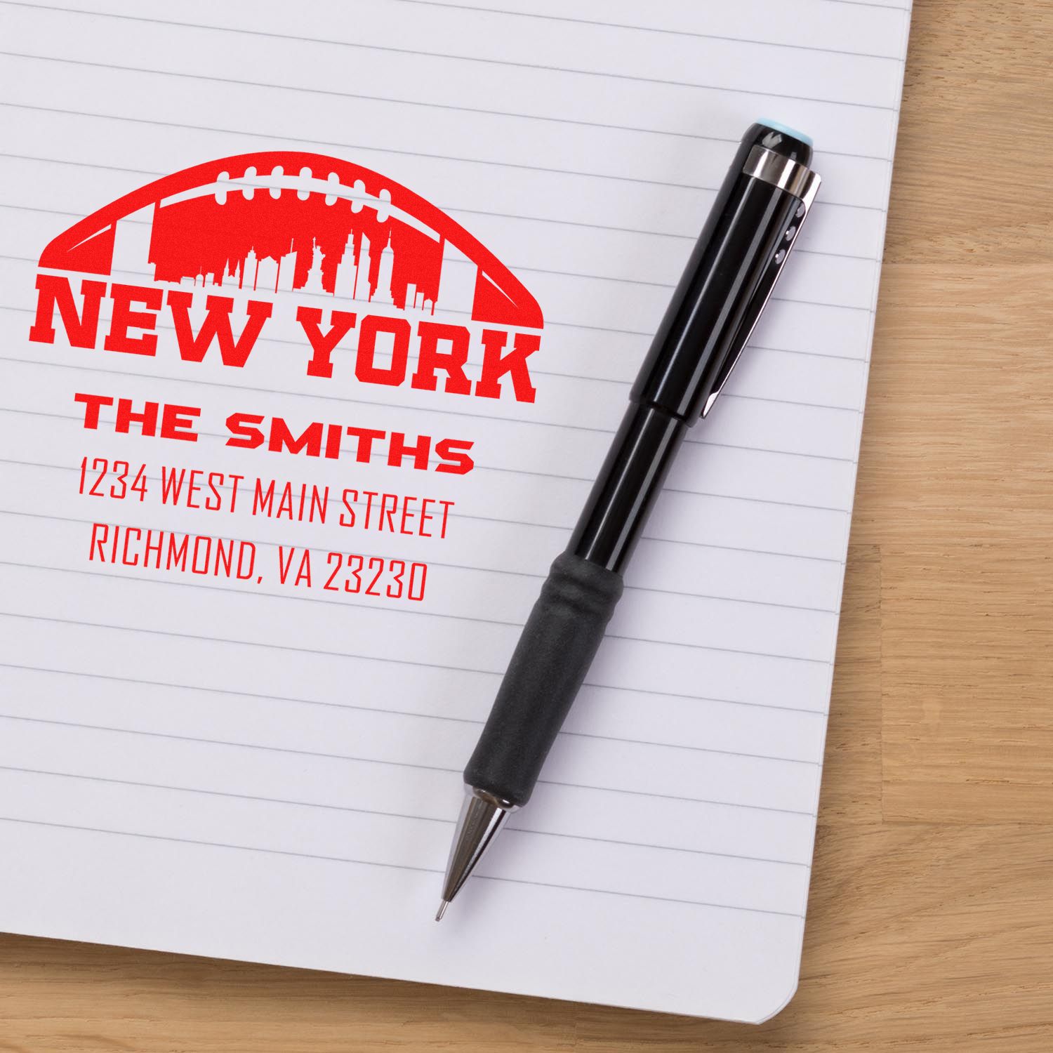 Custom address rubber stamp with New York skyline on notebook beside pen