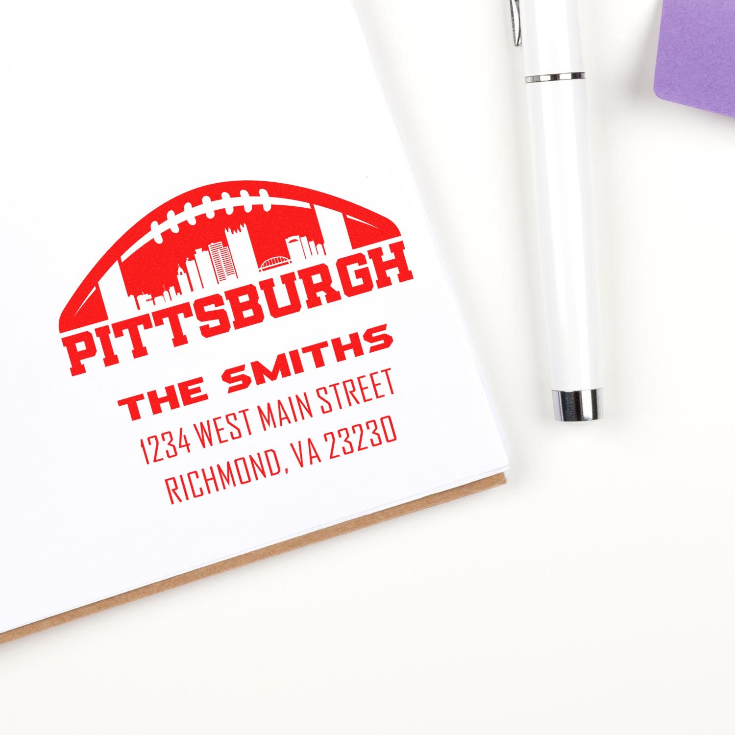 Custom Pittsburgh address rubber stamp with skyline and football design, printed on a notebook.