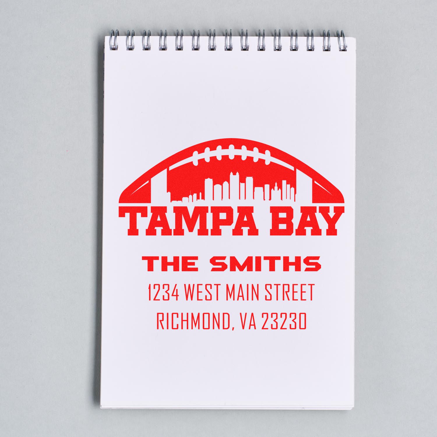 Custom rubber stamp impression with Tampa Bay skyline, The Smiths name, and address on a notebook for business branding.