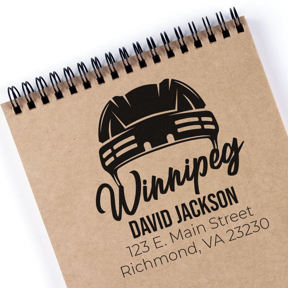 Custom construction rubber stamp with hard hat logo, name, and return address stamped on a kraft notebook.