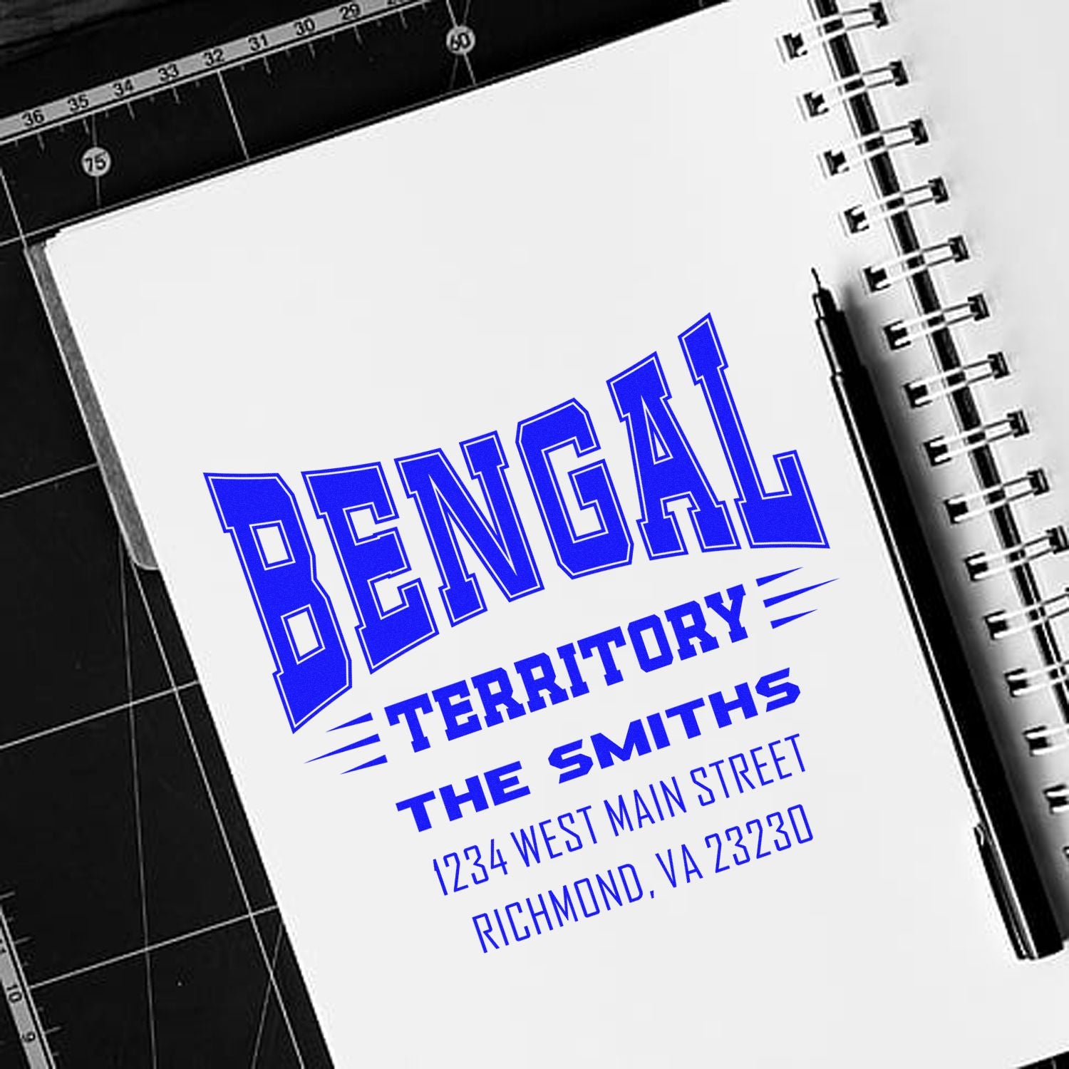 Personalized rubber stamp mockup showing a blue Bengal Territory address stamp for The Smiths on a notebook page.