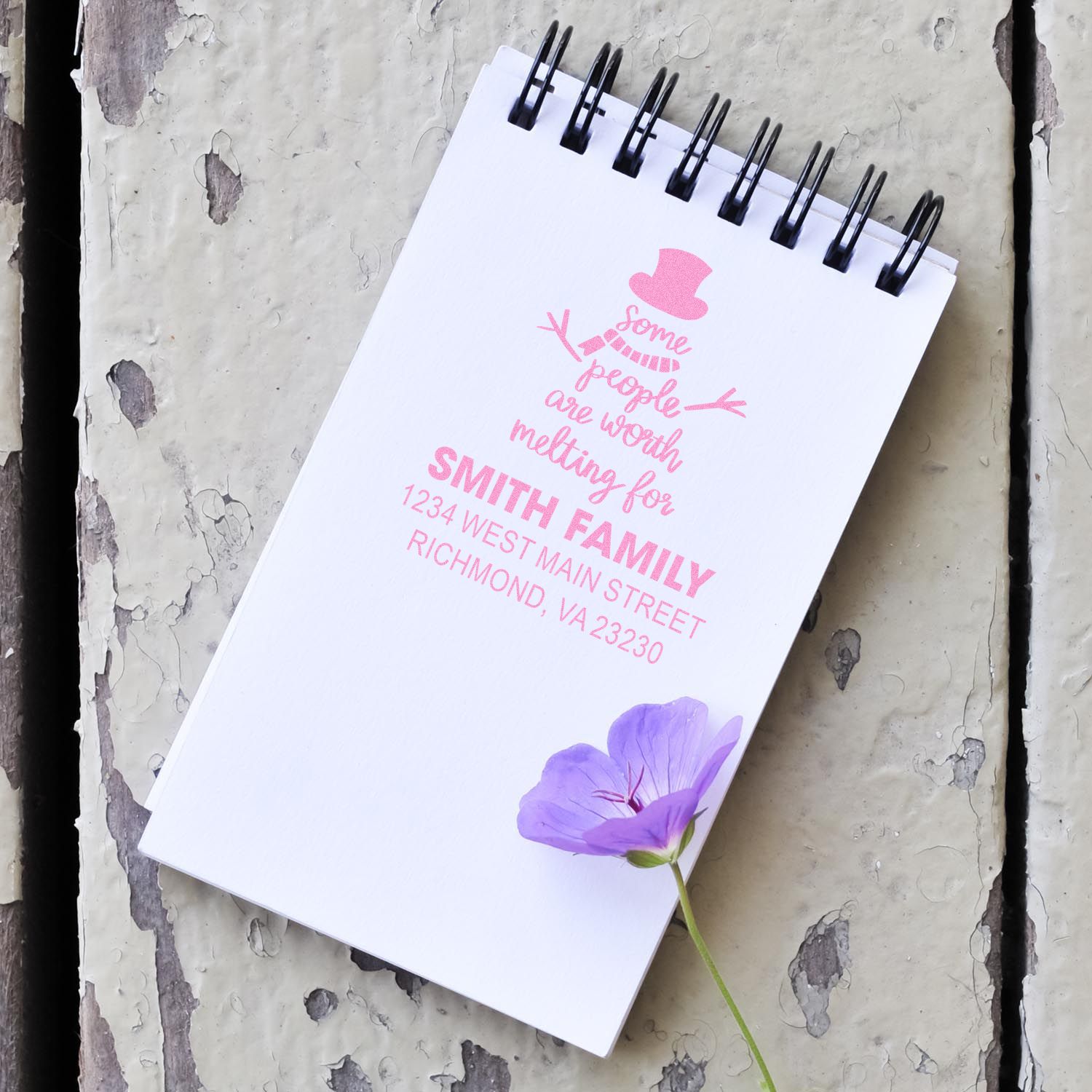 Custom personalized return address rubber stamp impression on a notebook, featuring a family name, quote, and mailing address.
