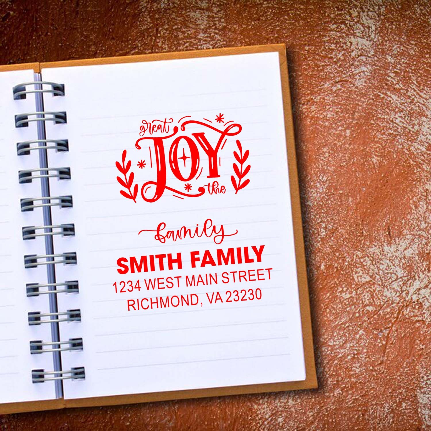 Custom family rubber stamp design in notebook, featuring Great Joy and Smith family name, address, and decorative wreaths.